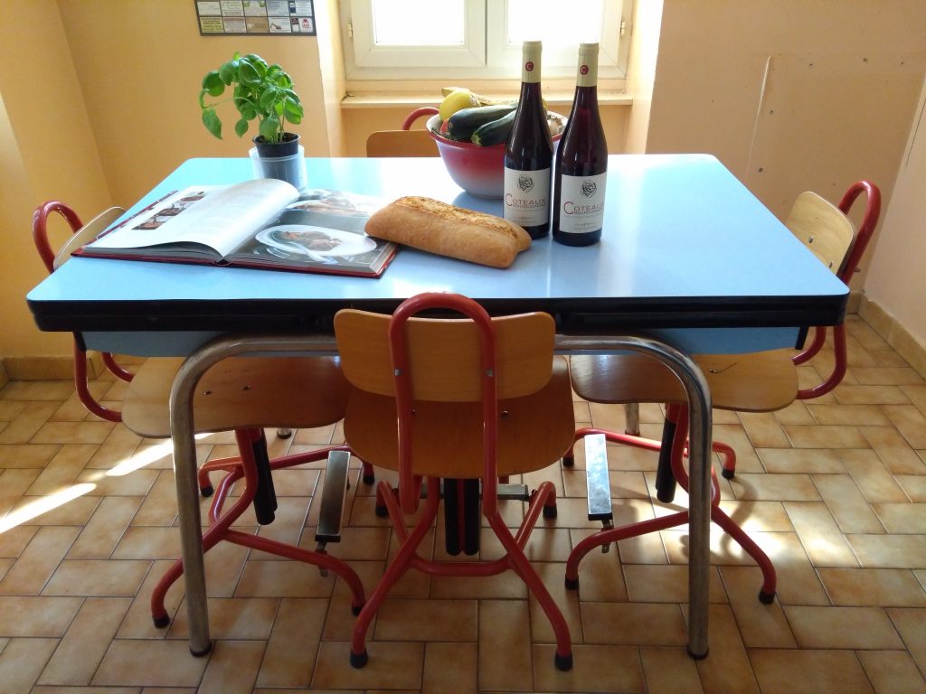 Tafel met flessen wijn, een kookboek en een brood.
